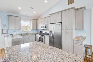 a kitchen with white cabinets and a stainless steel refrigerator at LaiDDback in Folly Beach