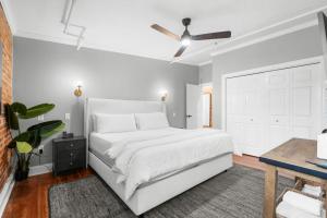 a white bedroom with a white bed and a ceiling fan at West End Loft - Downtown 5 min walk to River St in Savannah