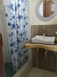 a bathroom with a sink and a blue and white shower curtain at Cabañas Riviera Pacific in Pedernales +56 photos