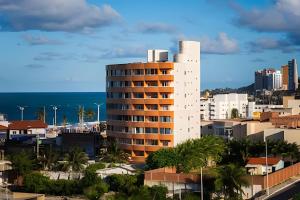 ein hohes weißes Gebäude mit dem Ozean im Hintergrund in der Unterkunft Apartamento beira-Mar em Natal in Natal