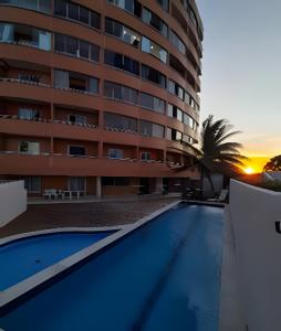 ein Hotel mit einem Swimmingpool vor einem Gebäude in der Unterkunft Apartamento beira-Mar em Natal in Natal