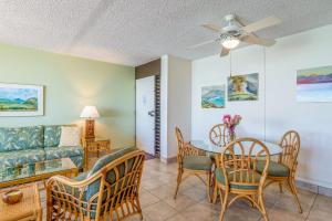 un soggiorno con un divano, un tavolo e delle sedie di Nohonani 203 a Kahana