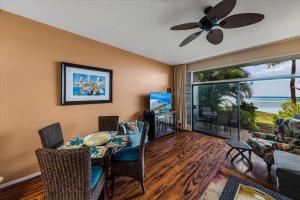 a living room with a table and chairs and a view of the ocean at Hale Mahina A102 in Kahana +18 photos