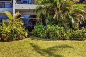 a building with palm trees and bushes in front of a yard at Hale Mahina A102 in Kahana