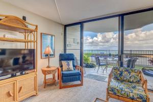 a living room with a tv and a view of the ocean at Kahana Reef 106 in Kahana