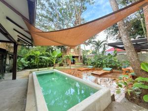 an outdoor swimming pool with a hammock over it at Alitaptap Villa by Lugadia Villas in El Nido