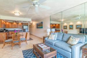 a living room with a blue couch and a kitchen at Kamaole Sands 2-106 in Wailea
