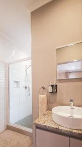 ein Badezimmer mit Waschbecken und Glasdusche in der Unterkunft Swakopmund Central Garden Guest House in Swakopmund