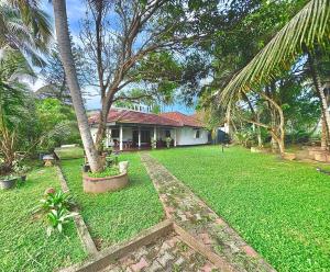 een huis met een tuin met palmbomen en gras bij Browns Hill Matara in Matara