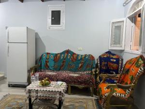 a living room with a couch and a table and a refrigerator at Nile Flower Guesthouse in Luxor