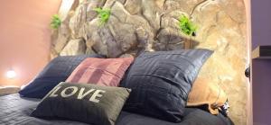 イエールにあるLX187 Ecrin d'Amour jacuzzi privé - cœur de Hyèresの石の壁のあるベッドの上に枕が積み重ねられている +9枚の写真