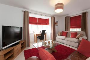 a living room with a couch and a television at DBS Serviced Apartments - The Mews in Castle Donington