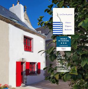 a white building with red windows and a red door at Le clos du prieuré - Les Gîtes de la Côte d'Amour in Batz-sur-Mer