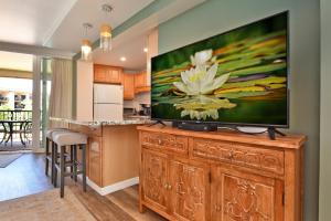 a living room with a large flat screen tv on a wooden entertainment center at Hale Ono Loa 203 in Kahana +18 photos