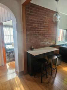 a kitchen with a brick wall and two bar stools at Renovated 1930's home in Sandy Bay