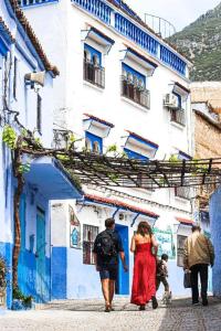 Un grupo de personas caminando por una calle frente a un edificio. en Dar amine, en Chefchaouen