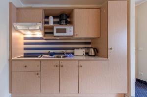 Ferienwohnung Deichperle - Ihr idyllischer Rückzugsort an der Ostsee in Zingst في زنغست: مطبخ مع خزائن خشبية وميكروويف +11 صورة