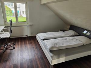 a bedroom with two beds and a desk and a window at Goldiger Berg - Pilatusweg 6 in Affoltern