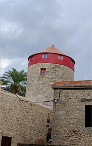 um edifício com uma torre vermelha no topo em A medieval windmill tower in the heart of old town with magnificent view em Rodes