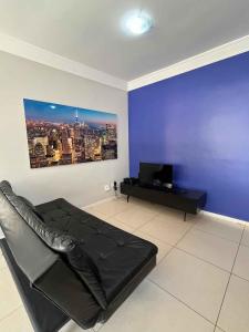 sala de estar con sofá negro y pared azul en LK Santo Antônio 1, en Belo Horizonte