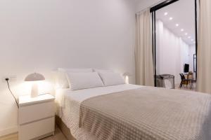 a white bedroom with a white bed and a window at Loft moderno recién reformado con patio en el centro de Elche in Elche