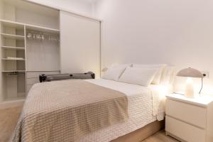 a white bedroom with a large bed and a lamp at Apartamento moderno recién reformado con patio en el centro de Elche in Elche