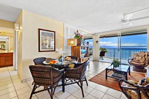 a living room with a table and chairs with a view of the ocean at Hololani A203 in Kahana