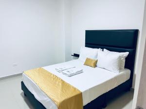 a bed with a blue headboard and white pillows at Habitacion con baño privado cali in Cali