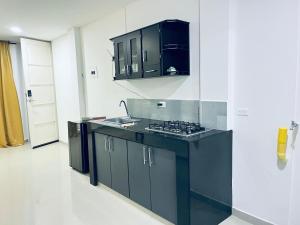 a kitchen with black cabinets and a stove top oven at Habitacion con baño privado cali in Cali