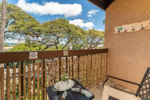 einen Balkon mit einem Tisch, einem Zaun und Bäumen in der Unterkunft Maui Vista 2414 in Kihei