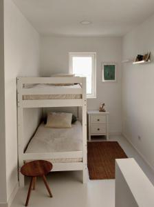 a white bunk bed in a white room with a stool at El Timón in La Santa