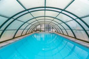 an indoor swimming pool with a glass ceiling at La Villa du Bonheur - Piscine - Jardin - Honfleur in Honfleur
