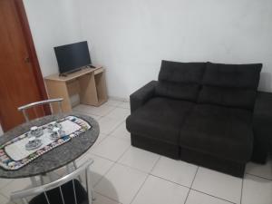 een woonkamer met een zwarte bank en een tafel bij Casa independente e aconchegante in Poços de Caldas