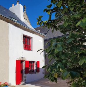 a white house with red windows and a red door at Le clos du prieuré - Les Gîtes de la Côte d'Amour in Batz-sur-Mer