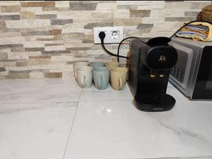 Una tostadora y cuatro tazas junto a un microondas. en Refugio tranquilo cerca de las piscinas, en Candeleda 3 fotos más