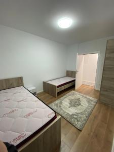 ein Schlafzimmer mit zwei Betten und einem Teppich in der Unterkunft L Apartaments in Peja