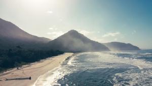 a view of a beach with a mountain in the background at Drop House Hostel - Surf & Skate - Itamambuca in Ubatuba