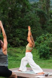 a woman performing a yoga pose on a blanket at Drop House Hostel in Ubatuba