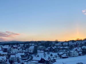 Ferienwohnung Auszeit am Waldrand في أولبه: بلدة مغطاة بالثلوج عند غروب الشمس