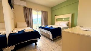 um quarto de hotel com duas camas e uma escrivaninha em Oasis do Mar Hotel - A melhor vista de Itapema em Itapema mais 100 fotografias