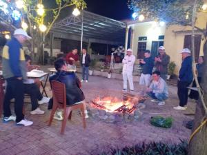 a group of people standing around a fire in a yard at Sun Mountain Hostel in Nguyên Ngoại