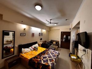a room with a bed and a couch and a television at The night view in Noida
