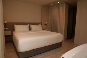 een slaapkamer met een groot bed met witte lakens en kussens bij VPV Suites & Casino in Medellín