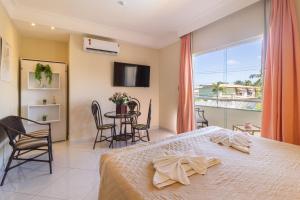 a bedroom with a bed and a table and chairs at Villa Araçà - Boutique Hotel in Lauro de Freitas
