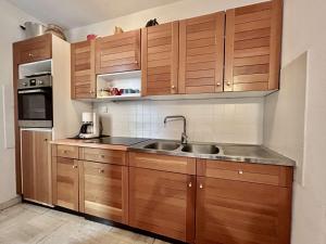 een keuken met houten kasten en een spoelbak bij Appartement lumineux 2 pièces + coin montagne, 6 couchages, proche commerces et pistes - Monêtier-les-Bains - FR-1-330F-32 in Le Monêtier-les-Bains