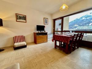 een eetkamer met een tafel en een televisie bij Appartement lumineux 2 pièces + coin montagne, 6 couchages, proche commerces et pistes - Monêtier-les-Bains - FR-1-330F-32 in Le Monêtier-les-Bains +14 foto's
