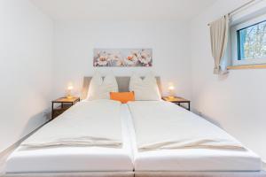 a large white bed in a room with two tables at Sund Huus in Altefähr