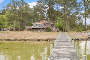 a house on the water with a wooden dock at Adventures on the Bay - Bayfront Escape, Private Dock, Large Deck, and Lake Views! in Hudgins