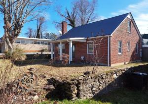 una casa di mattoni con un muro di pietra di fronte di The Copper Cottage on Main ad Abbeyville