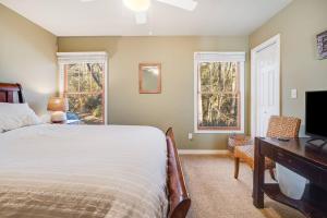 a bedroom with a bed and a desk and two windows at Serene Cabin Overlooking Large Pond in Brevard